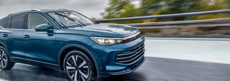Blue SUV driving on wet road. Power and technology in motion